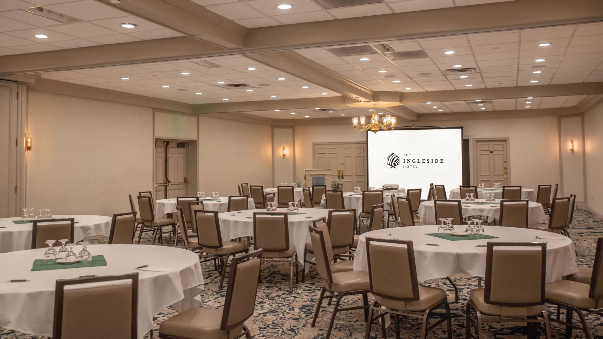 Fieldstone meeting space with round tables, water service, and a screen projector.