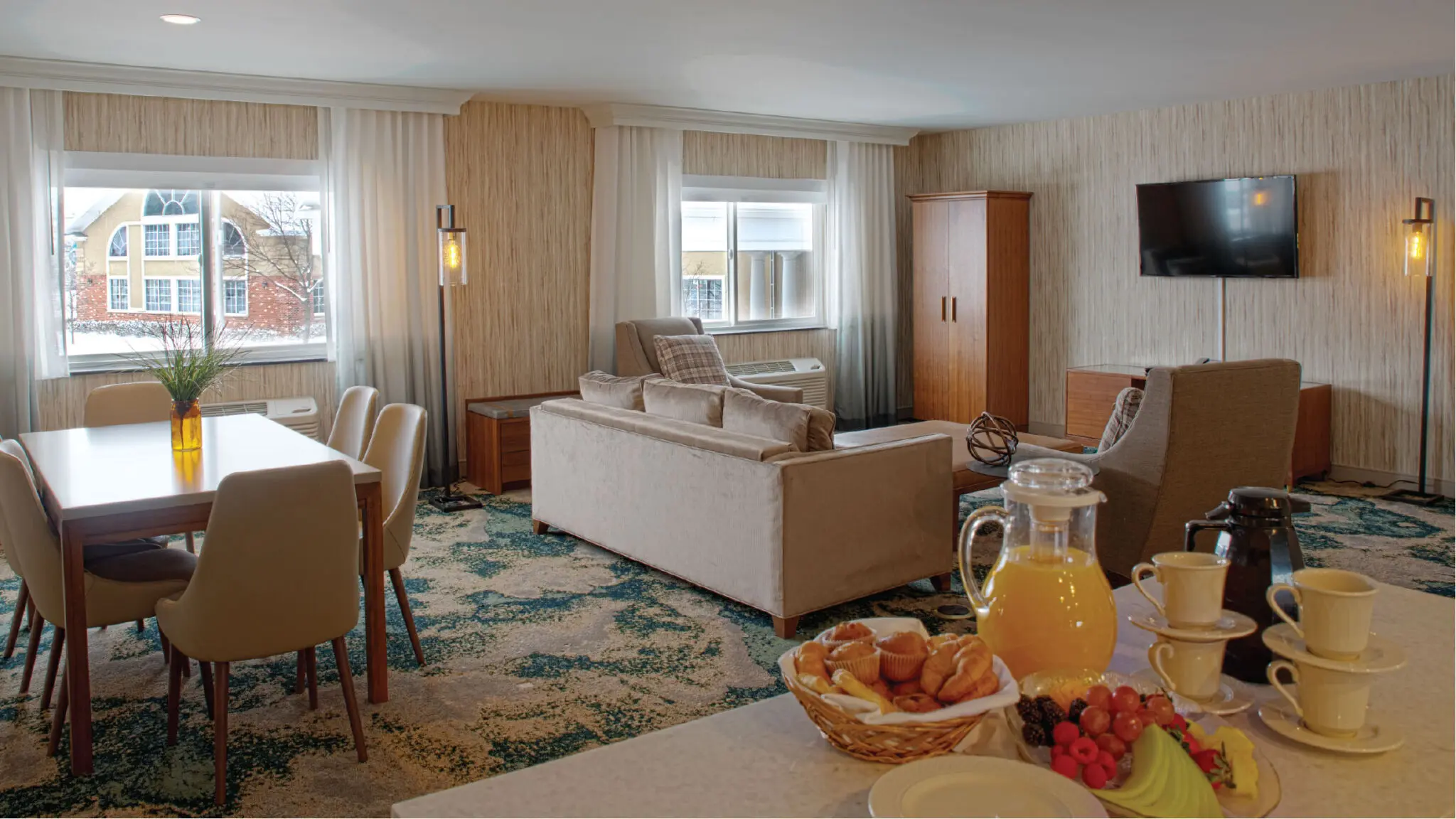Hospitality suite with a kitchenette, dining table, living room area and continental breakfast service.