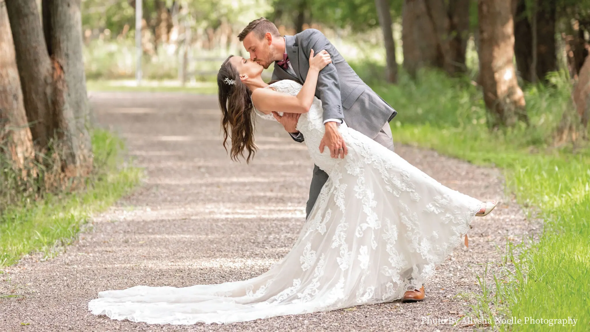 Wedding couple kissing on a wooded walking trail.