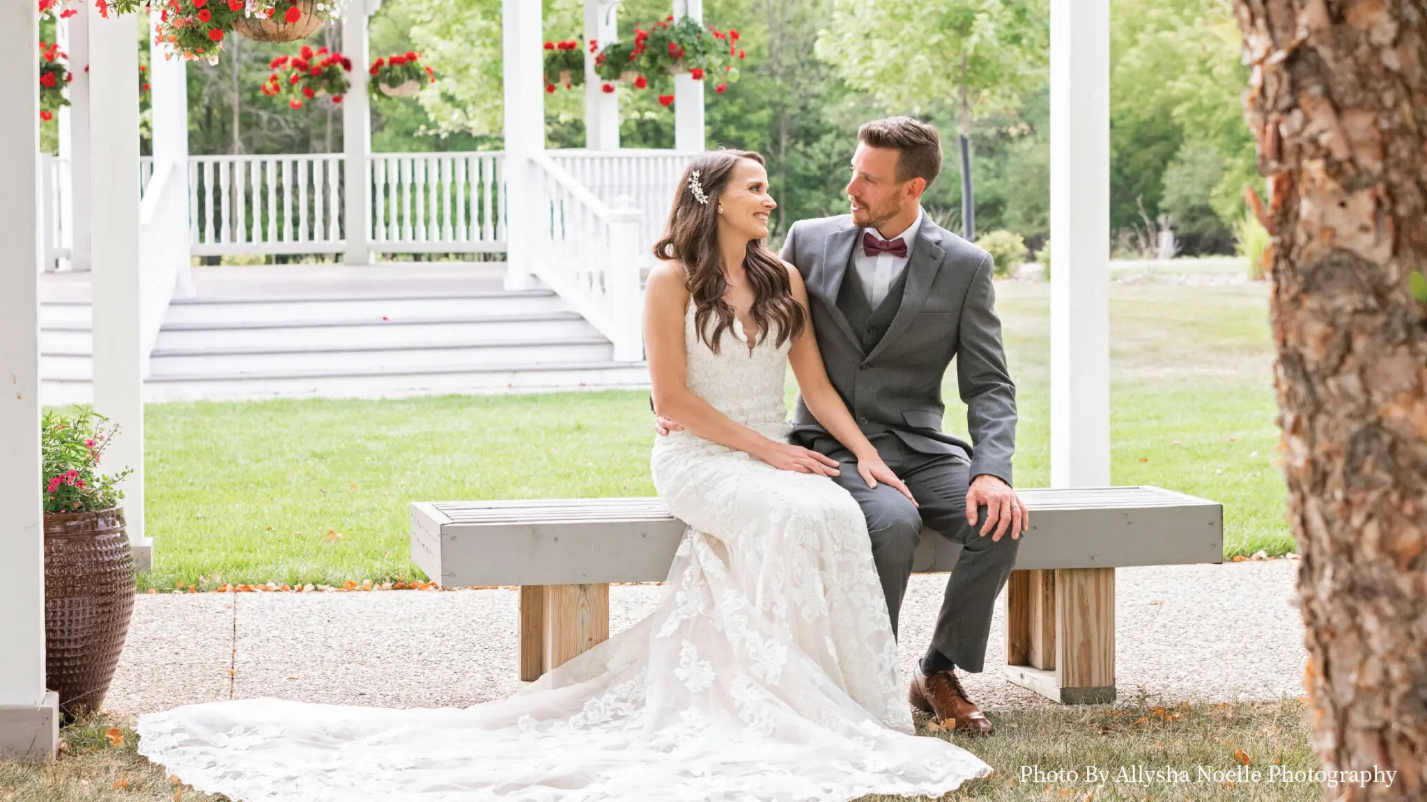 Wedding couple posing on a bench with the Ingleside Gazebo in the background.