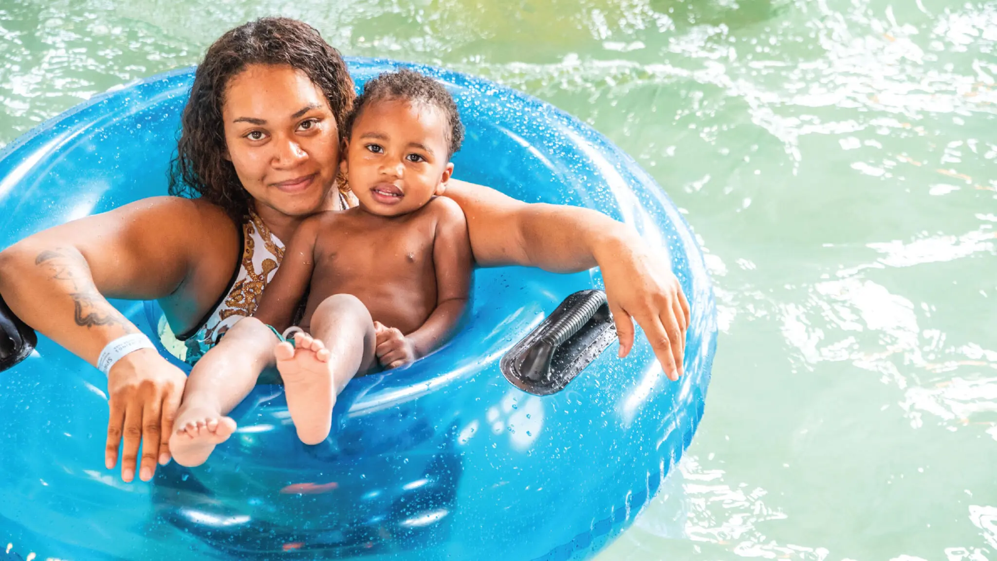 Mother and son on a blue tube floating in a lazy river.