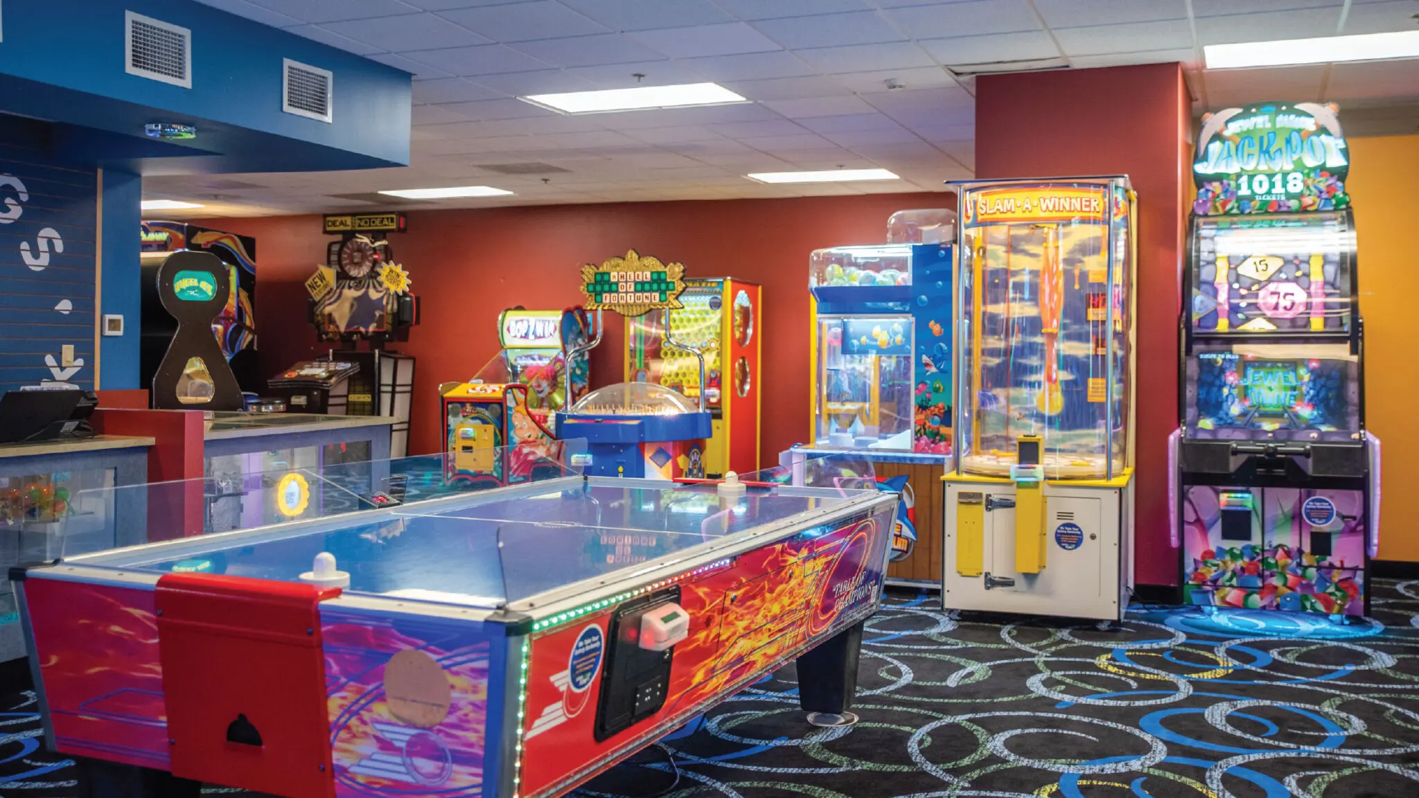 Geyser Games Arcade featuring an air hockey table, claw machines, and other arcade games.